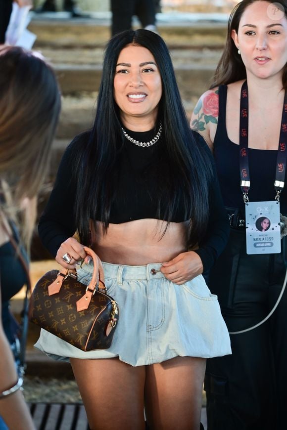 Simaria escolheu um look com top cropped preto, minissaia jeans volumosa e botas de cano alto