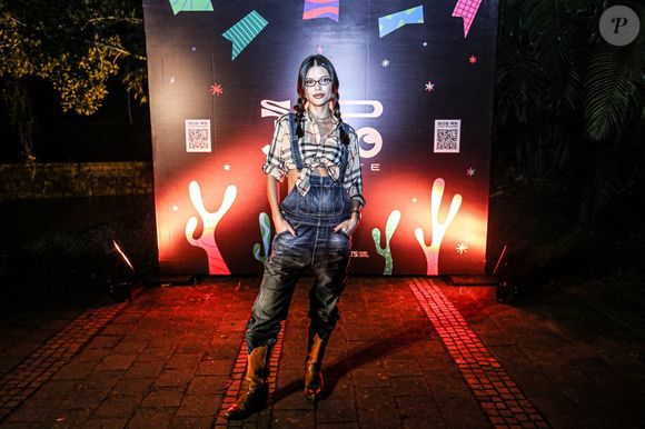 A atriz Vitória Strada combinou macacão jeans e blusa xadrez em look