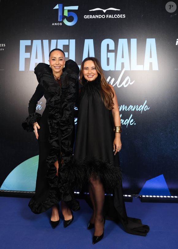 Kika Sato, irmã de Sabrina, escolheu a simplicidade sofisticada de um vestido preto fluido de gola alta, adornado com franjas sutis na bainha e complementado por um bracelete dourado marcante e uma clutch preta lisa
