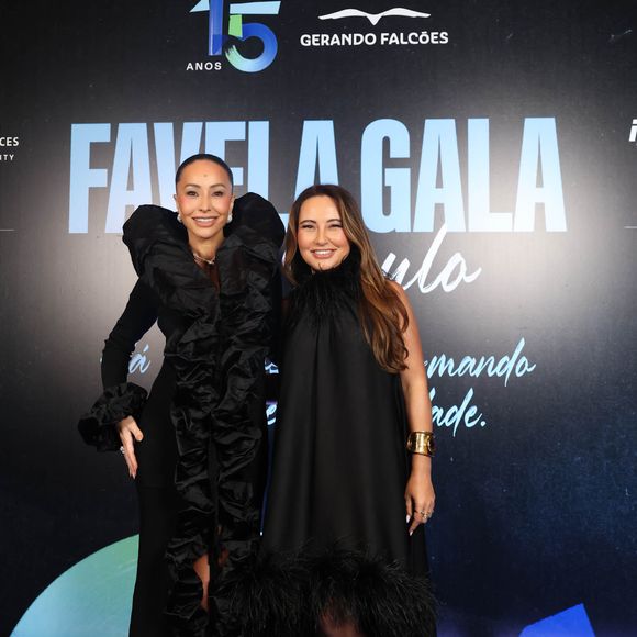 Kika Sato, irmã de Sabrina, escolheu a simplicidade sofisticada de um vestido preto fluido de gola alta, adornado com franjas sutis na bainha e complementado por um bracelete dourado marcante e uma clutch preta lisa