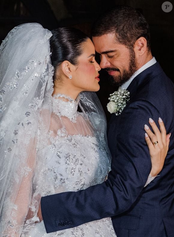 Com coque polido e buquê de rosas brancas, Luana Sales apostou em um vestido de noiva clássico para o casamento com Sidney Sampaio
