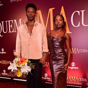 Breno Ferreira e Clara Moneke: Breno usou um conjunto casual de calça social e camisa de sarja bege aberta, enquanto Clara desfilou um vestido de couro marrom com decote coração, destacando uma estética minimalista e urbana