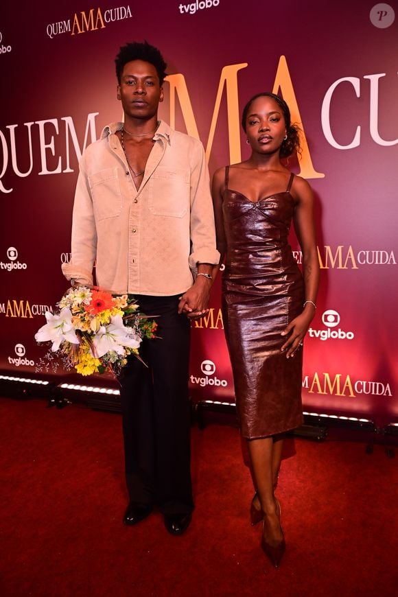Breno Ferreira e Clara Moneke: Breno usou um conjunto casual de calça social e camisa de sarja bege aberta, enquanto Clara desfilou um vestido de couro marrom com decote coração, destacando uma estética minimalista e urbana