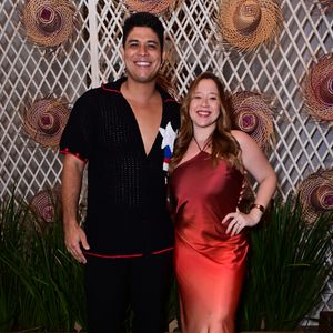 Guilherme e Letícia Tavares: ele vestiu uma camisa de tricô preta de mangas curtas com pontos abertos, gola polo e detalhes em linha vermelha e branca na lapela, além de calça preta e tênis brancos. Ela usou um vestido midi de cetim em efeito degradê que flui do tom vinho ao champanhe, com decote frente única e sandálias dourada