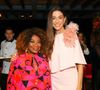 Mônica Martelli usa vestido rosa-claro com capa fluida e flores 3D no ombro durante evento do Outubro Rosa 2026; Zezé Motta também esteve presente