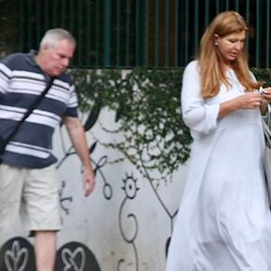 Roberta Close passeou sem maquiagem, com um vestido branco largo e fluido e uma bolsa