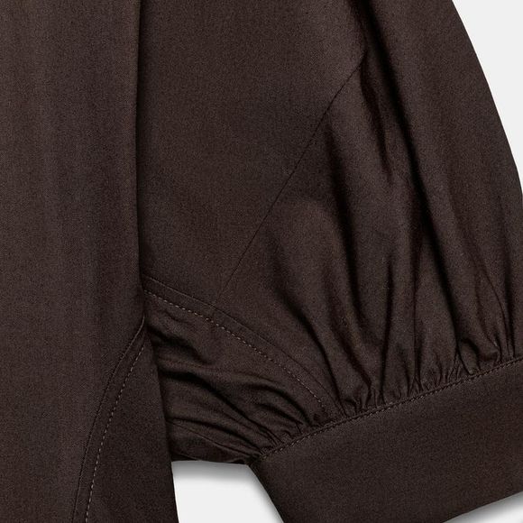 Por R$ 439, a Zara aposta em um vestido midi marrom com mangas bufantes e fechamento frontal por botões, daqueles que transitam facilmente do escritório ao jantar