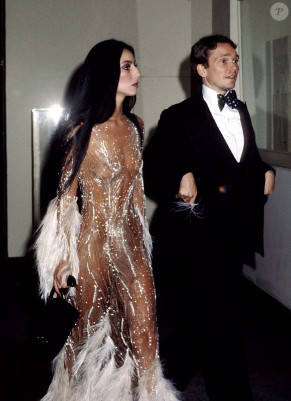 Cher e Bob Mackie durante o MET Gala de 1974. Conhecido por criações com brilho, miçangas, lantejoulas, strass e penas, o estilista vestiu alguns dos maiores nomes da história do entretenimento, de acordo com o New York Times