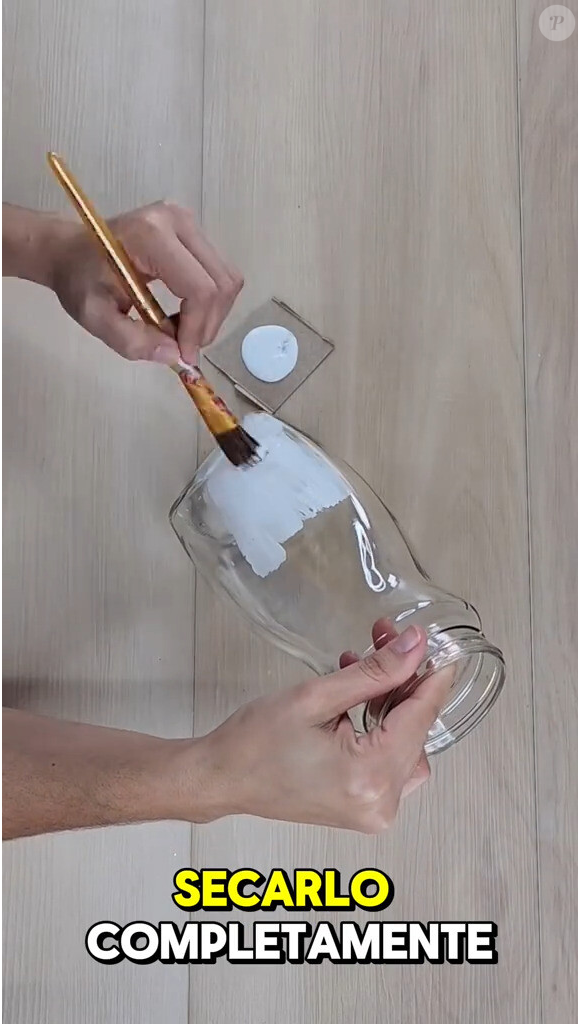 Primeiro, limpe bem o frasco, removendo os rótulos e qualquer resíduo de papel, deixando apenas o vidro liso. Em seguida, pegue um pincel com um pouco de cola e cubra o frasco.