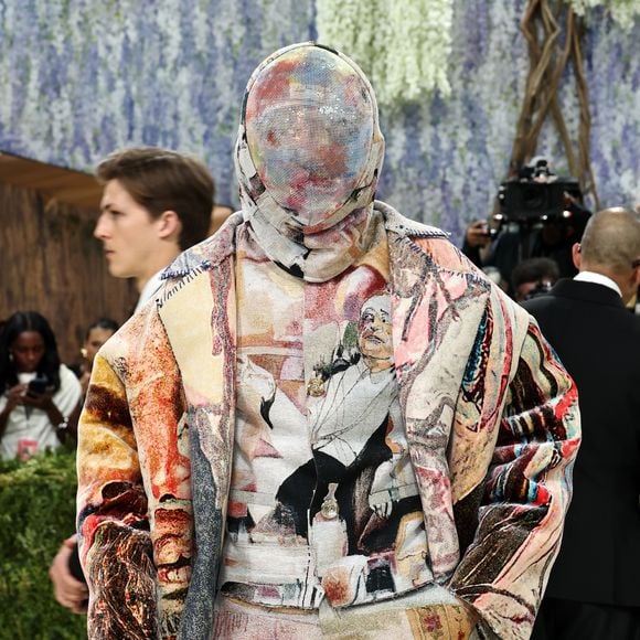 Miles Chamley-Watson A$AP elevou o conceito de arte vestível ao surgir completamente coberto por um conjunto de tapeçaria que reproduzia obras clássicas. Além do casaco e calças coordenados, Rocky utilizou uma máscara integral feita do mesmo tecido tramado, ocultando totalmente sua face e criando uma silhueta contínua que transformou o artista em uma galeria itinerante de texturas e cores