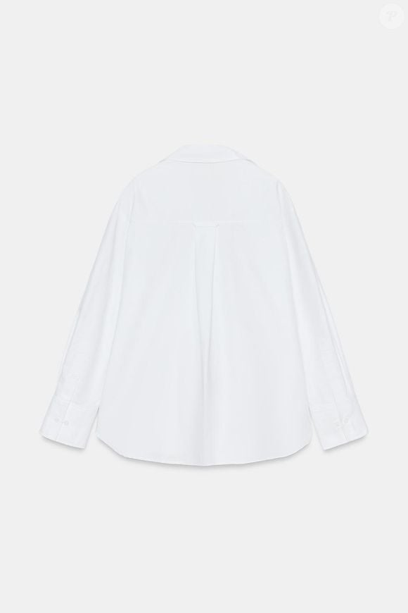 A Camisa Básica Oxford da Zara aposta em uma construção clássica com fio de algodão, gola de lapela, decote V e mangas amplas, além de fechamento frontal por botões