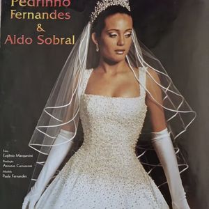 7. Vestido cravejado em pedraria

Esse é a síntese do glamour bridal dos anos 2000. Um vestido que une a sofisticação do corpete todo cravejado com pedrarias miúdas ao romantismo da saia ampla e volumosa. O corte quadrado do decote destaca os ombros e alonga a silhueta. A tiara cravejada e o véu estruturado arrematam o look. O vestido traz a mensagem de uma noiva poderosa, clássica e memorável, uma verdadeira "rainha" da passarela e do altar.