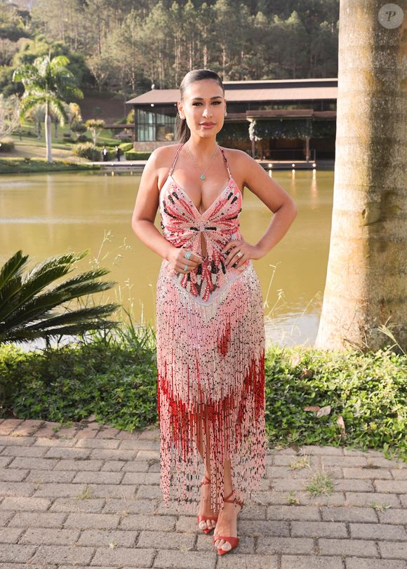 Simone Mendes surgiu deslumbrante em um vestido de festa que mistura sensualidade e sofisticação, perfeito para um casamento ao ar livre. A peça, em tom rosado com aplicações de paetês e pedrarias em vermelho, preto e prata, traz um desenho central que também lembra uma borboleta, criando um efeito marcante na região do busto e da cintura, onde há ainda um discreto recorte vazado