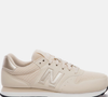 A tonalidade "espuma de latte" ajuda o New Balance 500V2 a entrar facilmente em diferentes produções, combinando com jeans, peças de alfaiataria e até com a clássica calça de veludo cotelê.