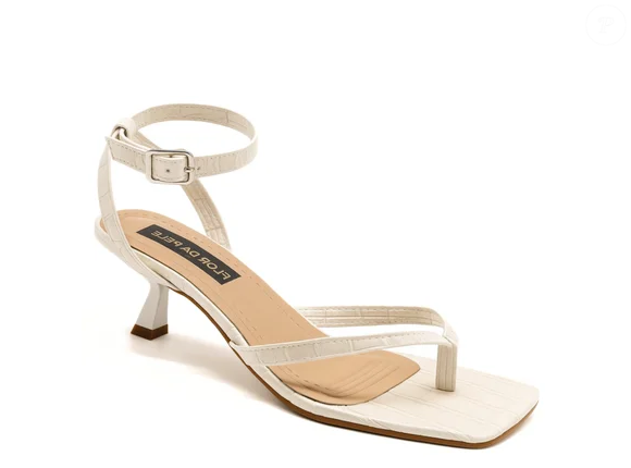 A Sandália de Dedo com Salto Kitten Heels da Flor da Pele, por R$ 145,26, traz salto de 5 centímetros e acabamento croco off white para uma produção minimalista e sofisticada