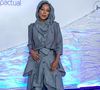 Negra Li: Look conceitual em alfaiataria desconstruída cinza risca-de-giz. Visual composto por blazer cropped de mangas 3/4 sobreposto a um colete assimétrico e calça oversized de modelagem utilitária ampla com amarrações, cordões suspensos e capuz acoplado cobrindo a cabeça