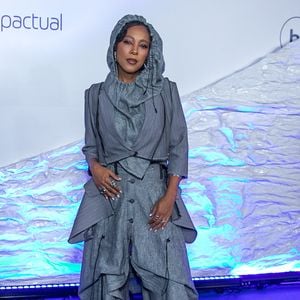 Negra Li: Look conceitual em alfaiataria desconstruída cinza risca-de-giz. Visual composto por blazer cropped de mangas 3/4 sobreposto a um colete assimétrico e calça oversized de modelagem utilitária ampla com amarrações, cordões suspensos e capuz acoplado cobrindo a cabeça