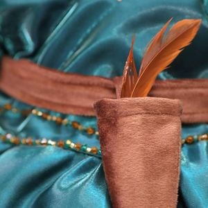 Detalhe da faixa com a pena no vestido da pequena, inspirado no filme da Disney