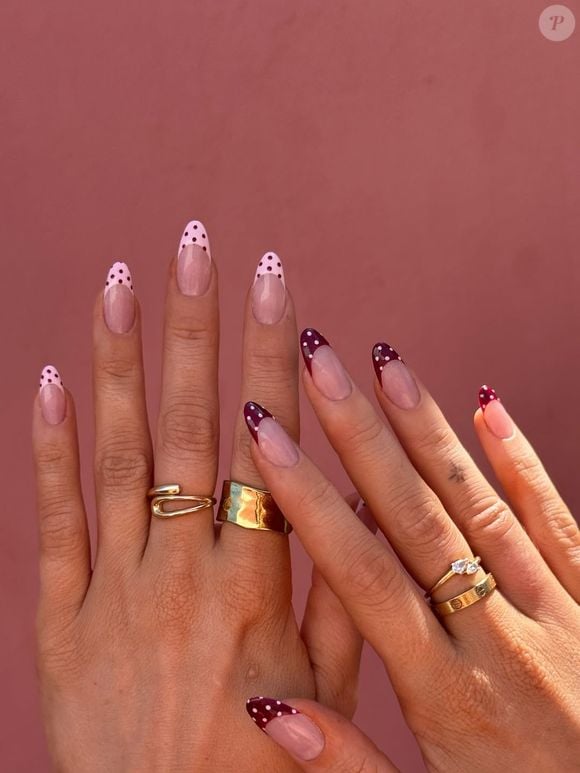 Unhas 2026: Alternar as cores das pontas entre as mãos cria a sensação de duas manicures em uma. Vermelho cereja com poás rosa de um lado; rosa com poás cereja do outro