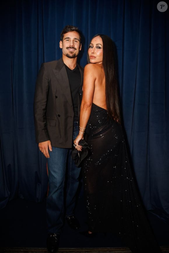 Sabrina Sato apostou num vestido longo preto exuberante com brilhos e pedrarias reluzentes espalhadas por toda a peça. O modelo destaca-se pelas costas totalmente descobertas e por um caimento fluido com cauda leve. Nos acessórios, optou por brincos redondos prateados bem marcantes, pulseiras delicadas e anéis brilhantes, além de manicura com unhas escuras compridas