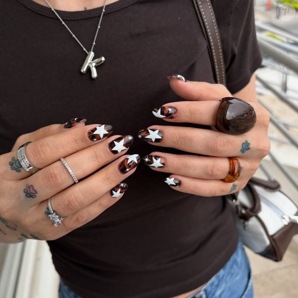 Unhas estrelas com animal print: para quem ama ousar, a mistura de estampa animal print com grandes estrelas brancas resulta em uma manicure impactante e cheia de atitude