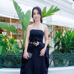 Klara Castanho trouxe uma proposta de alta costura com um vestido preto escultural de tafetá. A peça, sem alças, destaca-se pelo volume orgânico e arquitetônico nos quadris, criando uma silhueta 'ampulheta' moderna e imponente. O detalhe mestre da produção é o cinto largo com aplicações de flores tridimensionais e um ornamento central metálico em dourado, que quebra a monocromia com um toque artístico