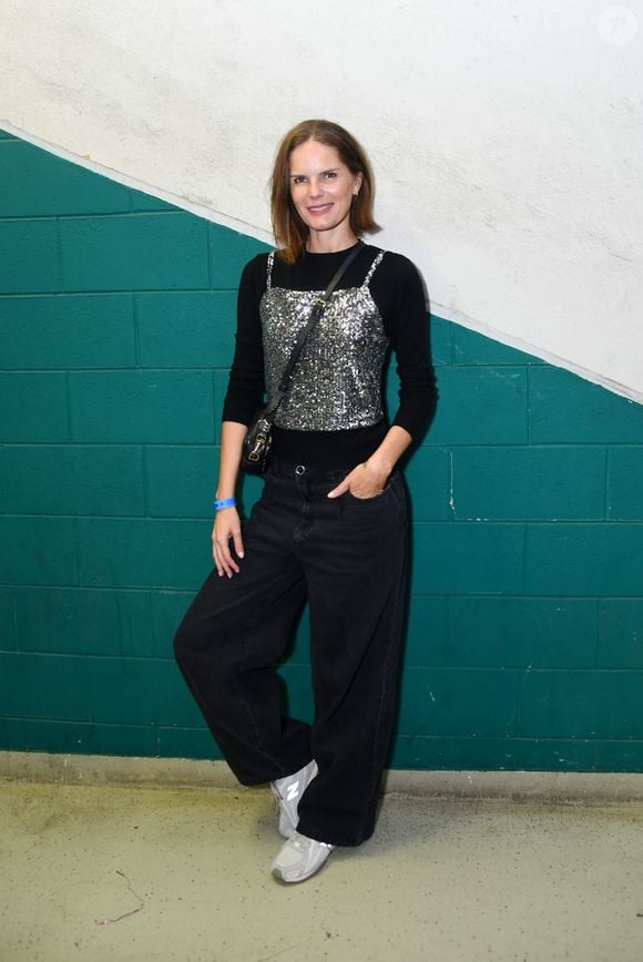 Marcelle Bittar apostou na sobreposição urbana ao combinar uma blusa preta de mangas longas sob um top corset de paetês prateados. O caimento despojado ficou por conta da calça jeans preta em modelagem wide leg e o par de tênis esportivos cinza