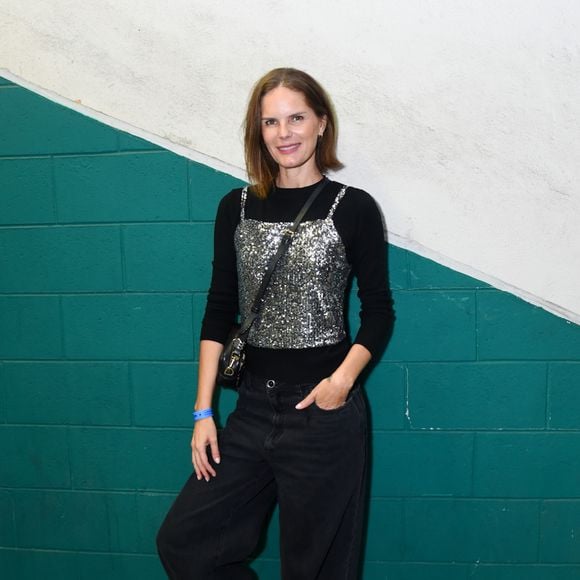 Marcelle Bittar apostou na sobreposição urbana ao combinar uma blusa preta de mangas longas sob um top corset de paetês prateados. O caimento despojado ficou por conta da calça jeans preta em modelagem wide leg e o par de tênis esportivos cinza