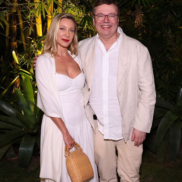 Vanessa Bueno e João Emanuel Carneiro: Ela usou vestido midi branco de decote coração franzido com echarpe e bolsa de palha; ele optou pelo conforto com blazer de linho bege, camisa branca por fora da calça clara e tênis esportivo