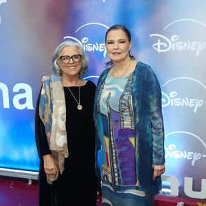 Guida Viana e Louise Cardoso: Guida aposta em um vestido preto clássico sobreposto por lenço estampado em tons neutros e colar com pingente; Louise veste um modelo fluido com estampa artística em tons de azul e roxo acompanhado por casaquinho combinando