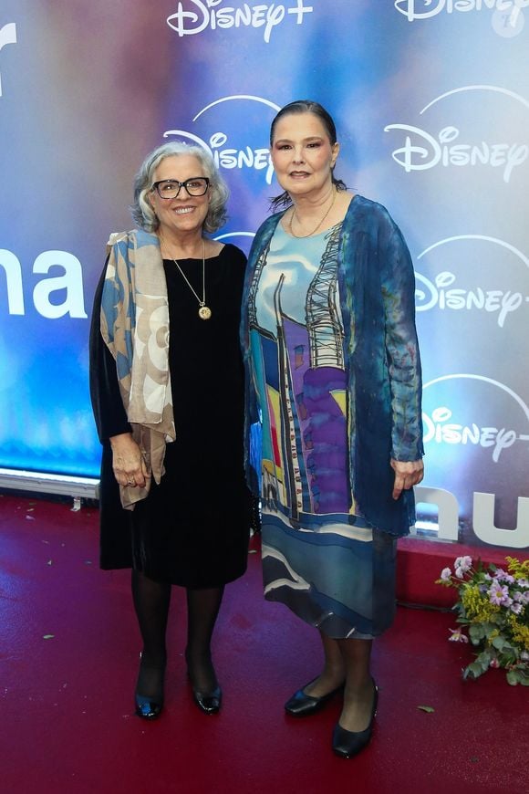 Guida Viana e Louise Cardoso: Guida aposta em um vestido preto clássico sobreposto por lenço estampado em tons neutros e colar com pingente; Louise veste um modelo fluido com estampa artística em tons de azul e roxo acompanhado por casaquinho combinando