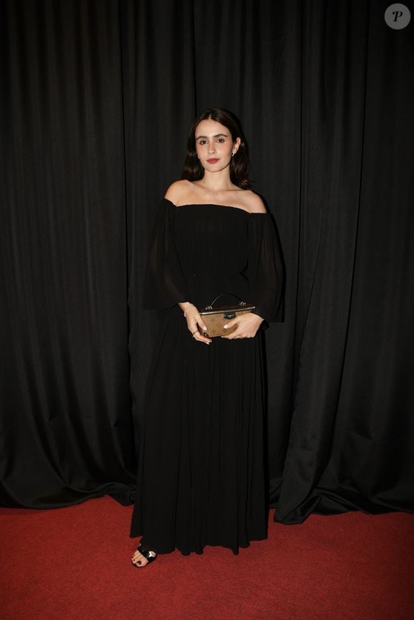 Valentina Herszage usou um vestido preto longo de mangas compridas, com decote ombro a ombro e saia plissada. A produção foi finalizada com sandálias pretas e uma bolsa marrom