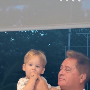 Leonardo coloca o dedo no gargalo da bebida e, em seguida, leva o dedo no canto da boca do neto