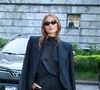 Sasha optou por um conjunto total black composto por um blazer oversized de ombros estruturados sobre uma blusa de gola alta em seda e calças de corte reto impecável, finalizando com óculos escuros estilo cat-eye e uma bolsa de mão estruturada