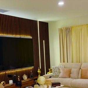 A decoração da mansão de Rick Sollo aposta em tons de bege, marrom e branco, presentes nos móveis e nos elementos decorativos. A sala de estar tem dois sofás e uma poltrona, enquanto a cozinha conta com ilha central e piso de madeira.