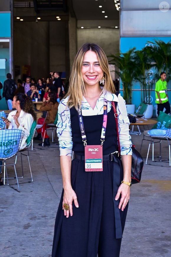O novo preppy: Daphne Bozaski aposta em sobreposições criativas no Rio2C; a atriz traz uma ótica jovem e descontraída para a tendência corpcore ao combinar uma camisa de botões com estampas abstratas em tons de azul sob um macacão preto de alfaiataria com pernas largas e cinto embutido