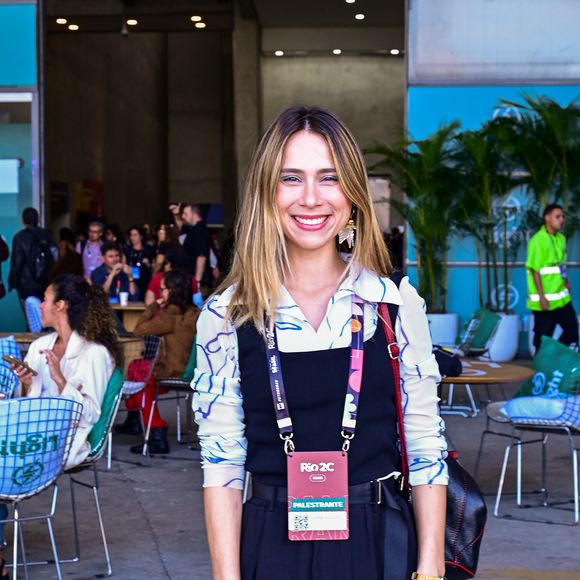 O novo preppy: Daphne Bozaski aposta em sobreposições criativas no Rio2C; a atriz traz uma ótica jovem e descontraída para a tendência corpcore ao combinar uma camisa de botões com estampas abstratas em tons de azul sob um macacão preto de alfaiataria com pernas largas e cinto embutido