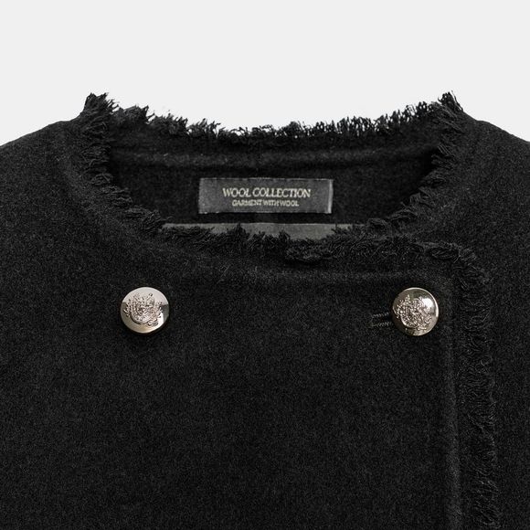 O casaco transpassado da Zara conta com acabamentos desfiados e fechamento frontal com botões metálicos, detalhes que acrescentam sofisticação à peça