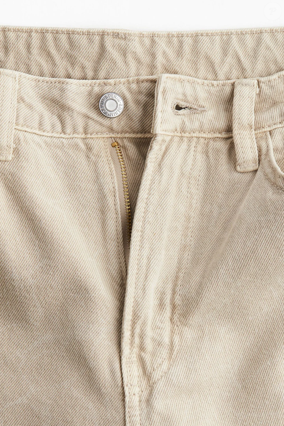 Com modelagem wide leg e cintura alta, a calça jeans bege da H&M ajuda a compor produções casuais que combinam com a estética clássica do New Balance 471