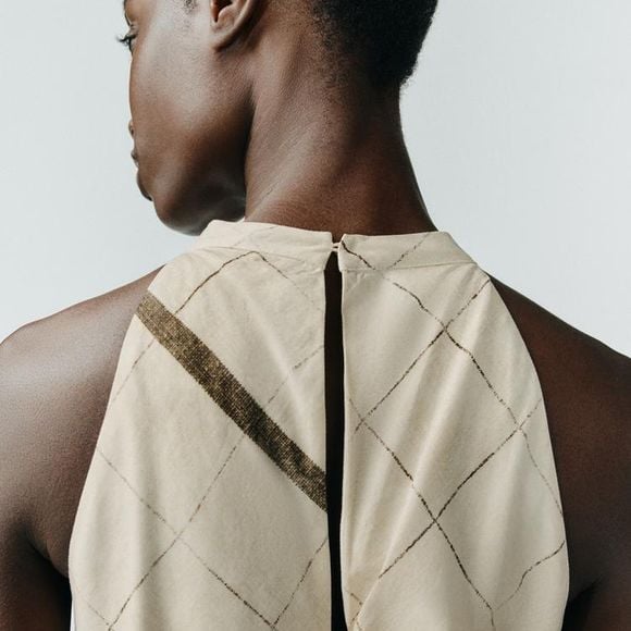 O segredo está na gola halter e na silhueta solta, com detalhe de abertura sutil que valoriza o corpo. A estampa abstrata sobre fundo branco e a barra assimétrica dão o toque moderno. Custa R$ 439,00