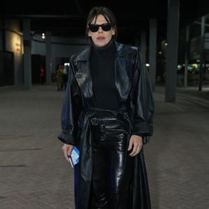 Bárbara Paz: look rocker monocromático em couro preto com sobretudo longo, blusa de gola alta, calça de couro brilhante, óculos escuros e botas de plataforma alta com sola clara