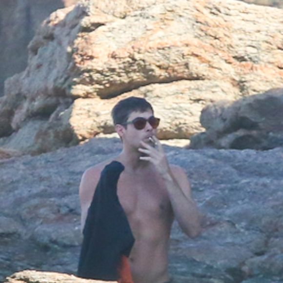 Rafael Vitti fumou um cigarro perto das pedras antes de trajar a roupa de surf