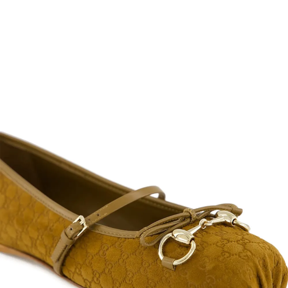 Já o detalhe metálico dourado "horsebit" no topo, acompanhado de pequenos elementos que lembram pedrarias delicadas, eleva o calçado ao status de peça-desejo