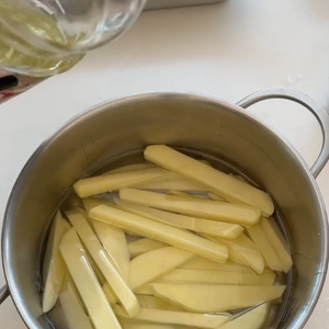 Coloque as batatas para uma frigideira ou panela com óleo frio e leve para fritar em temperatura baixa, sem mexer com garfo