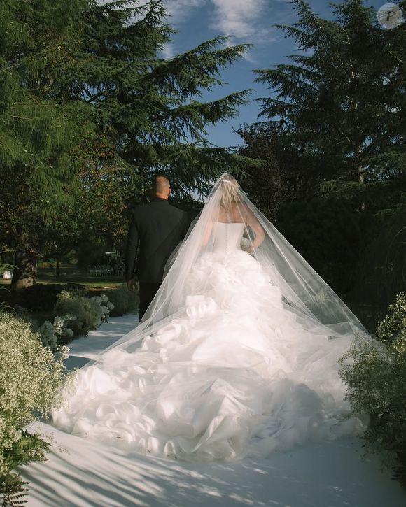 A escolha do vestido seguiu uma estética romântica e atemporal. Com saia volumosa em camadas e estrutura esculpida, o modelo branco transmite sofisticação, enquanto o véu longo adiciona um toque de tradição ao visual.