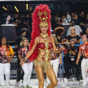 Também musa do Salgueiro, Cintia Dicker elegeu um look mínimo nas cores dourado e vermelho com uma coroa gigantesca