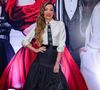 Patrícia Poeta apostou em uma estética 'preppy chic' com referências diretas à alta costura clássica. O conjunto é composto por uma camisa de seda off-white com mangas levemente bufantes e punhos ajustados, combinada a uma saia midi preta de tafetá com volume estruturado e cintura alta marcada por um cinto largo. O grande destaque da produção é a gravata preta estreita, adornada com diversos broches de luxo, incluindo o icônico logo da Chanel e elementos em pedraria