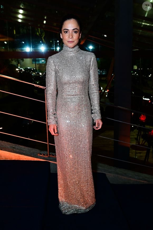 Alice Braga: a atriz apostou em um vestido longo reto inteiramente bordado com microbrilhos prateados. A peça possui gola alta e mangas longas. O penteado é um coque puxado e alinhado, acompanhado de maquiagem suave e unhas pintadas de escuro