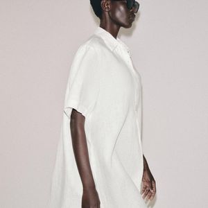 Para quem gosta de vestido branco soltinho, a Zara tem uma versão em linho que combina gola com lapela, mangas curtas e fechamento frontal por botões, além de barra arredondada com aberturas laterais. A peça custa R$ 439,00
