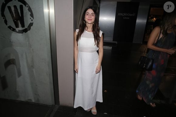 Maria Clara Senra usou um vestido branco longo, com transparência discreta na parte superior e sandálias claras